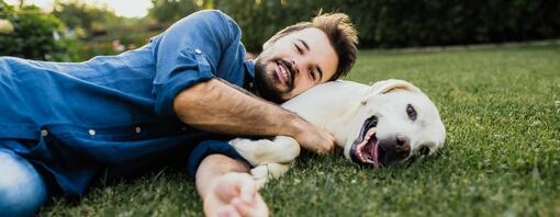 Guy and his Labrador retriever having a cuddle outdoors