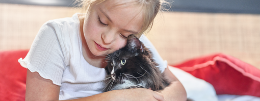 Young child cuddling cat